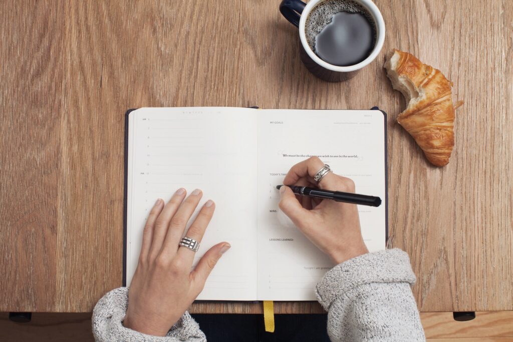 person writing on a planning book