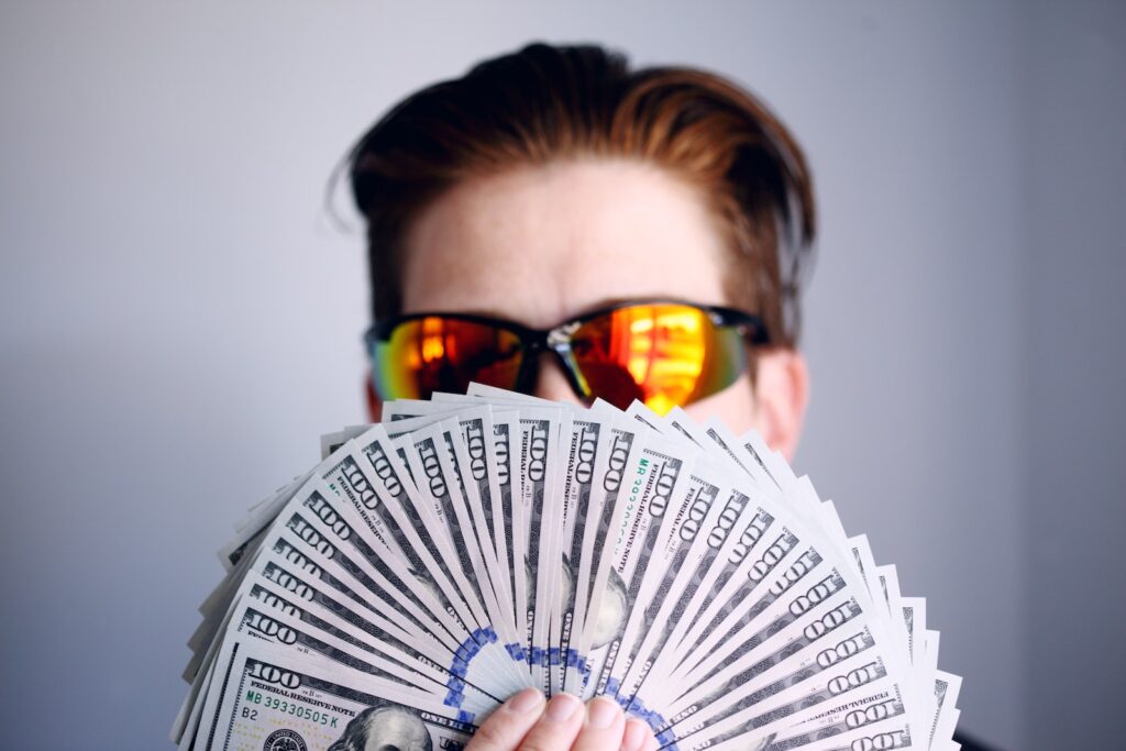 man in black framed sunglasses holding fan of money