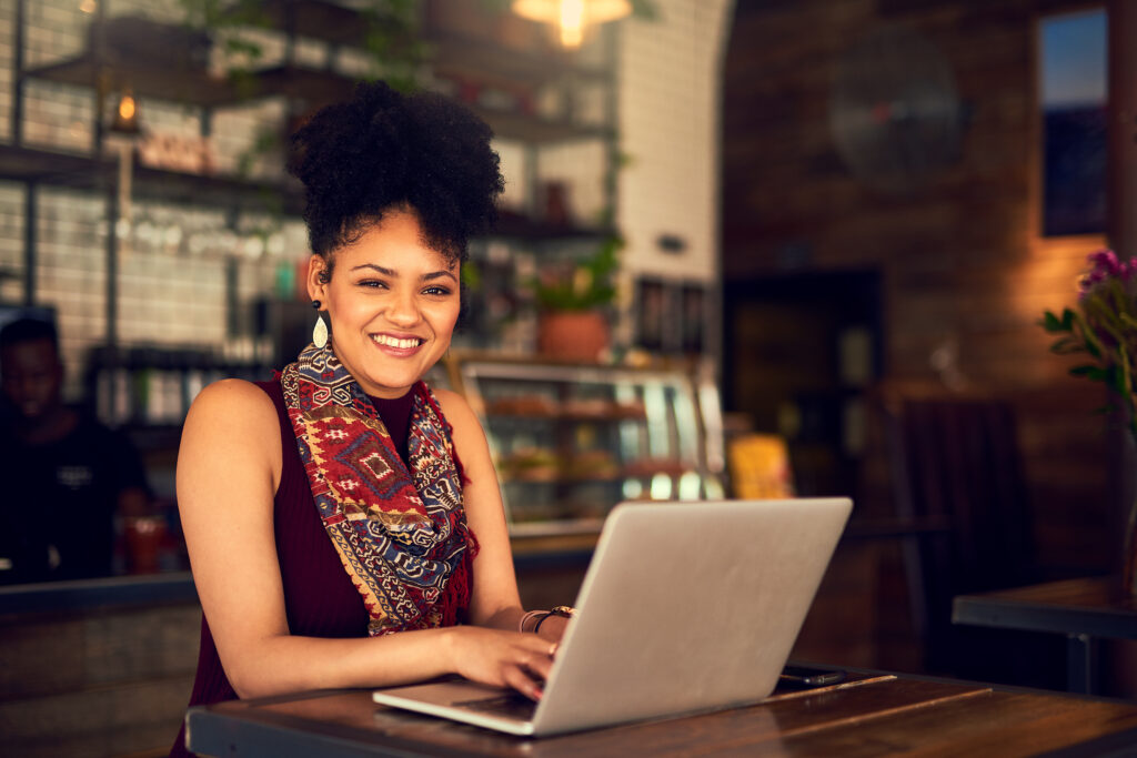 Woman smiling, sitting in front of a computer.