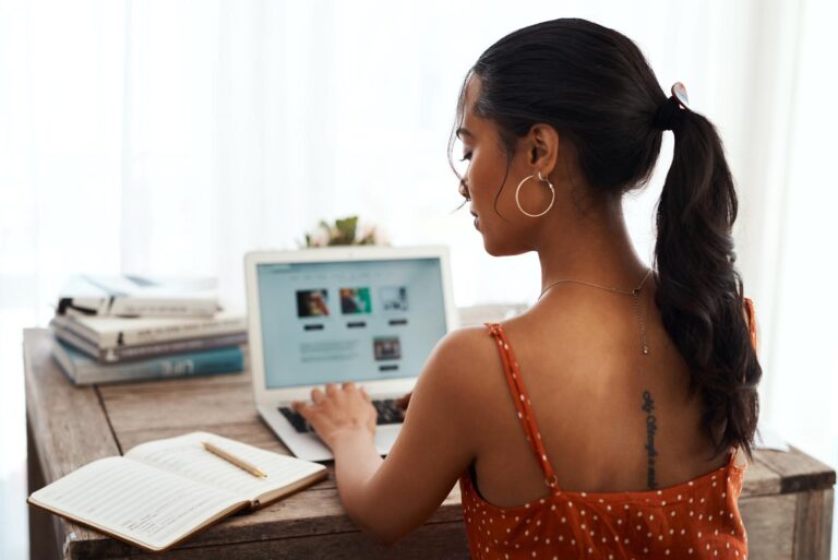 hecking my notes. Cropped shot of an unrecognizable businesswoman sitting alone in her home office and blogging from her laptop.